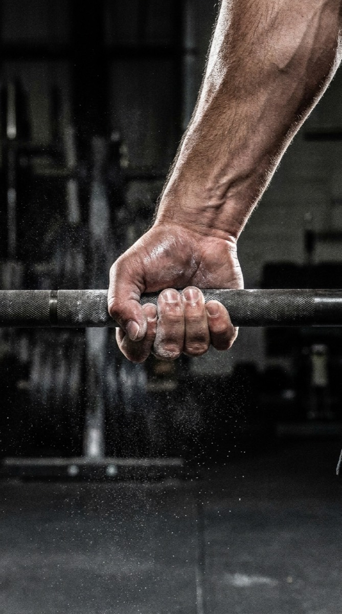 Main couverte de magnésie serrant une barre de musculation